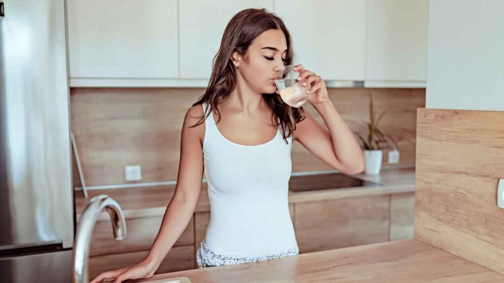 A woman taking a sip from a glass of water.