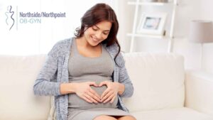 A pregnant woman sitting on a sofa, smiling and enjoying a joyful moment.