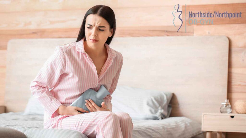 A woman sitting on a bed, with a pained expression.