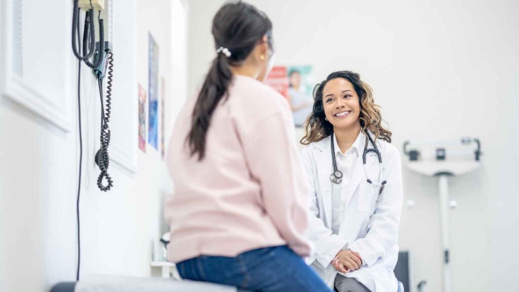 Female patient talking to a doctor during a regular health checkup in a clinic setting.