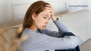 Woman sitting alone on a sofa, looking worried.