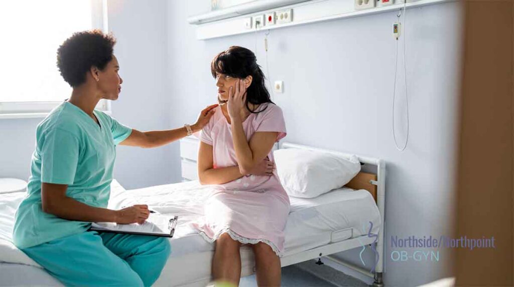Female patient in hospital bed having a discussion with her OBGYN doctor