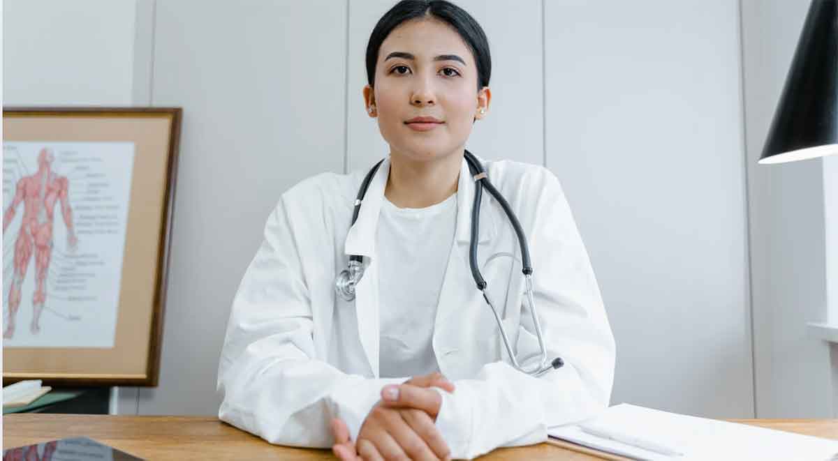 Confident OBGYN specialist in medical coat sitting in a clinic setting