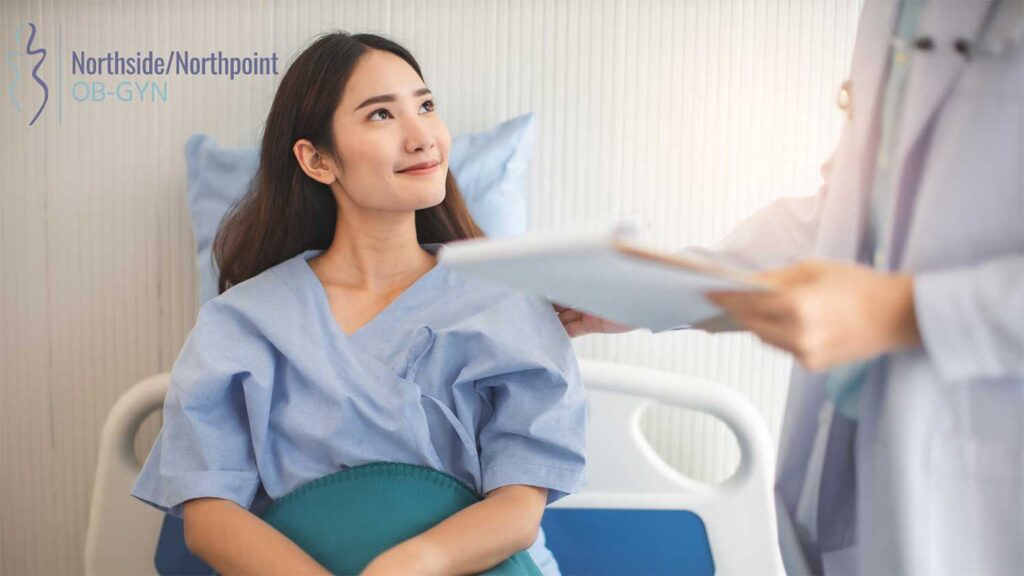Smiling woman sitting on a hospital bed, listening to her doctor