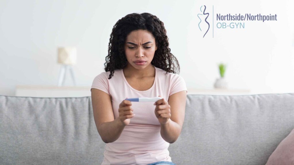 A woman looking disappointed while viewing a pregnancy test result.