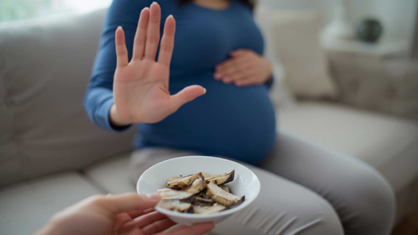 Pregnant woman refusing a bowl of cooked king mackerel.